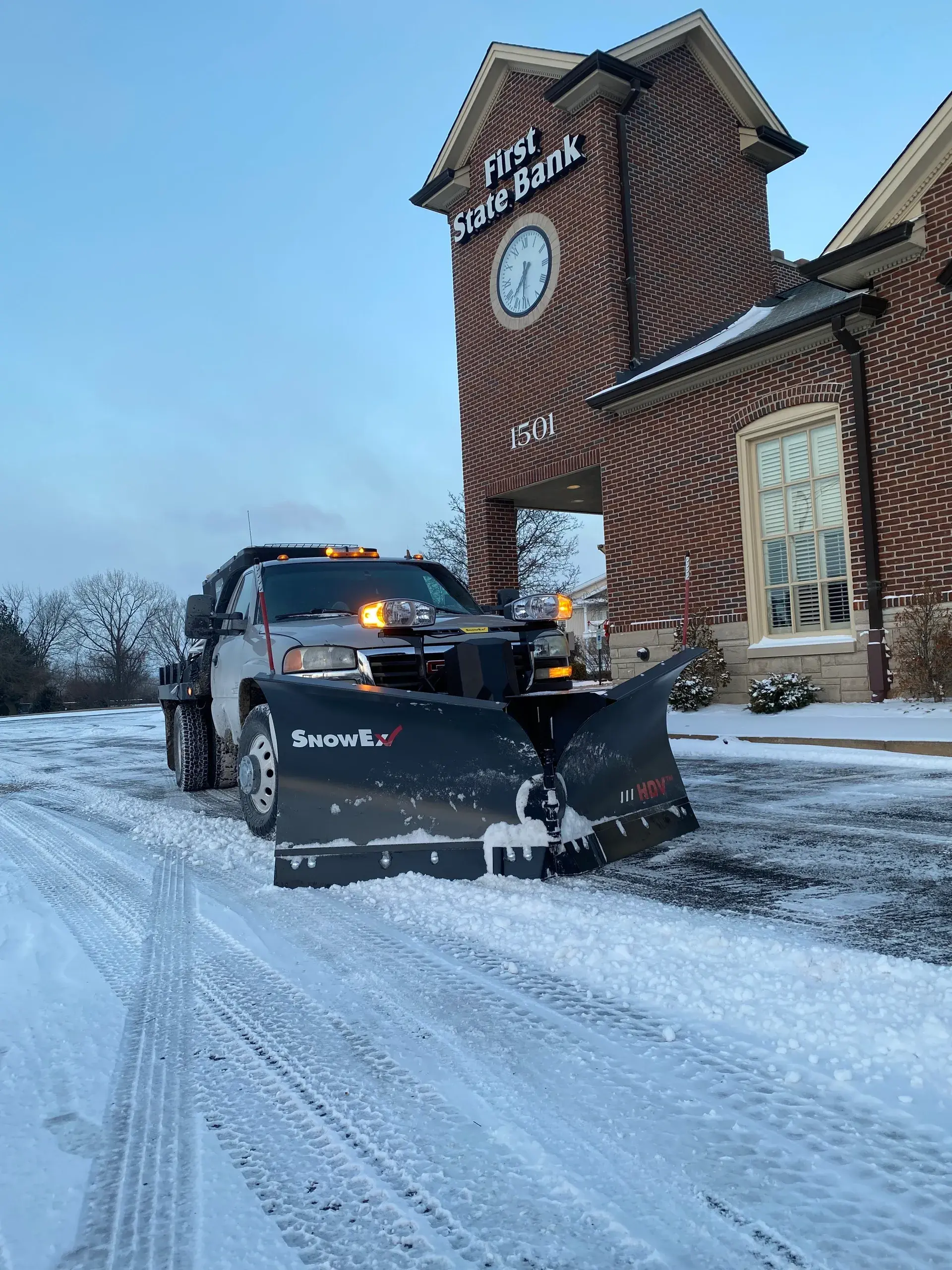 Professional snow removal service in St. Louis, MO with Porter's Lawn Service truck equipped with snow plow attachment clearing snow from roadway